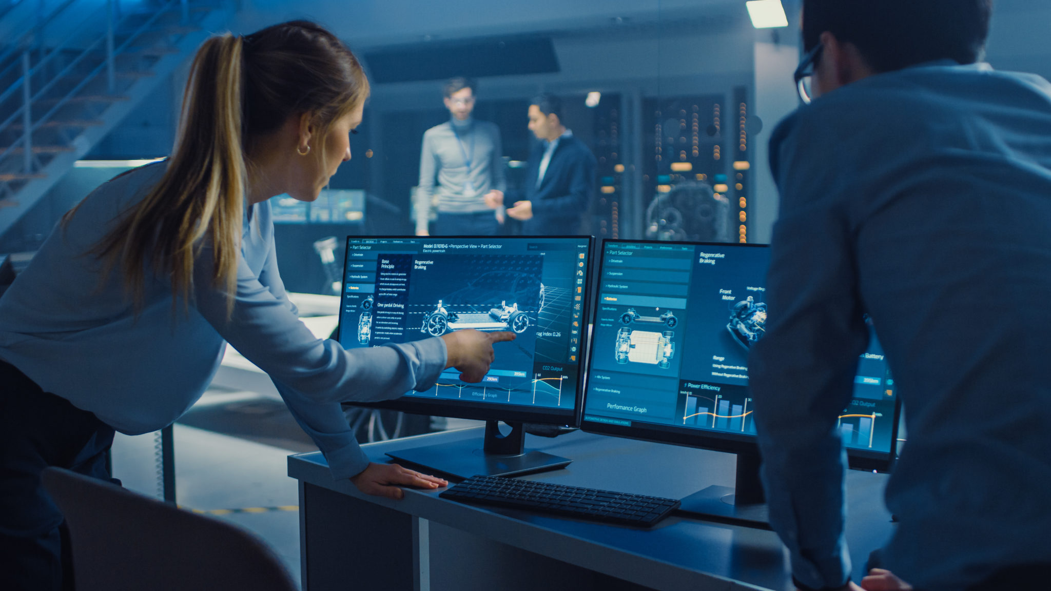 Female and Male Engineers are Discussing the 3D CAD Software Render of an Electric Concet Car. High Tech Laboratory with a Prototype Vehicle Chassis.